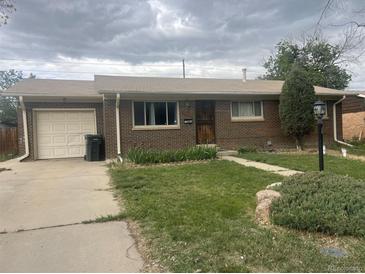 Charming brick home with a well-manicured lawn, lush landscaping, and a convenient attached garage at 12899 E Nevada Ave, Aurora, CO 80012
