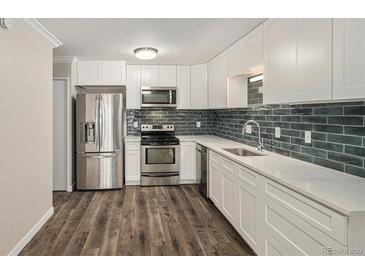 Modern kitchen features stainless steel appliances, white cabinets, and subway tile backsplash at 3460 S Poplar St # 404, Denver, CO 80224