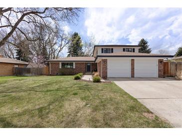 Charming brick home featuring an attached two-car garage and well-manicured lawn and landscaping at 1581 S Kendall St, Lakewood, CO 80232