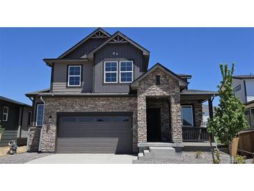 Beautiful two-story home featuring a stone and siding exterior, attached two-car garage, and covered porch at 6065 Caribou Dr, Brighton, CO 80601
