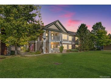 Charming condo building with lush green lawn, mature trees, and inviting covered porch and upper balcony at 4385 S Balsam St # 10-103, Littleton, CO 80123