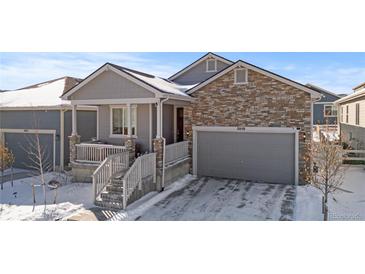 Two-story home with stone and siding accents, snowy front yard, and attached garage at 2058 Spencer Ave, Castle Rock, CO 80104