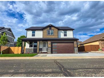 Two-story home featuring stone accents, a modern garage door, and a well-manicured lawn at 5550 Wetlands Dr, Longmont, CO 80504