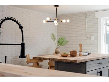 Bright kitchen island features a wood countertop and black pendant lighting at 1020 Stuart St, Denver, CO 80204