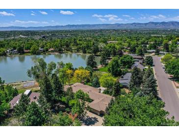 Breathtaking aerial view of a lakeside home surrounded by lush greenery and distant mountain views at 4790 W Lakeridge Rd, Denver, CO 80219