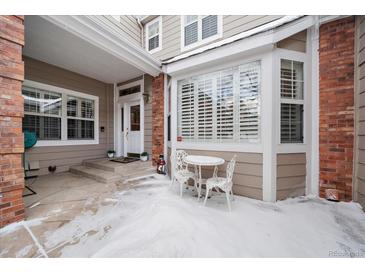 Inviting townhouse entrance with snow-covered patio and small table and chairs at 9875 Greensview Cir, Lone Tree, CO 80124