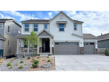 Beautiful two-story home featuring a gray two car garage and a charming covered porch at 3955 Descent St, Castle Rock, CO 80108