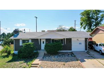 Brick ranch home with attached garage, landscaping, and a spacious driveway at 7609 Sherman Pl, Denver, CO 80221