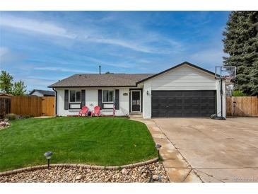 Charming single-story home featuring a well-manicured lawn, attached garage, and red lawn chairs at 9664 W Grand Ave, Littleton, CO 80123