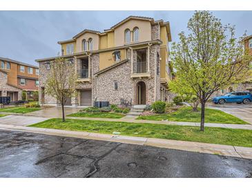 Attractive multi-story townhouse featuring stone accents, private balconies, and a well-maintained lawn at 9470 Loggia St # D, Highlands Ranch, CO 80126