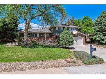 Charming two-story home with a well-maintained lawn, mature trees and a basketball hoop above the garage at 7521 S Race St, Centennial, CO 80122