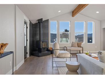 Bright living room features a wood burning fireplace and large windows with mountain views at 11725 Tomahawk Trl, Conifer, CO 80433