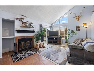 Cozy living room featuring a brick fireplace, vaulted ceilings, and abundant natural light at 4086 S Carson St # F, Aurora, CO 80014