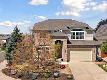 Charming two-story home featuring a brick facade, manicured landscaping, and a two-car garage at 7869 Solstice Way, Castle Rock, CO 80108