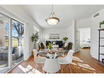 Bright living room with hardwood floors, modern decor, dining area, and view to a bedroom at 12924 Ironstone Way # 103, Parker, CO 80134