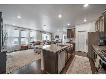 Open-concept kitchen and living area featuring granite countertops, stainless steel appliances, and abundant natural light at 11442 Booth Falls Ct, Parker, CO 80134