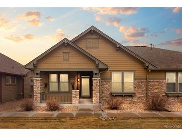 Charming single-Gathering home featuring stone accents, a covered front porch, and manicured landscaping at 8555 W Quarles Pl, Littleton, CO 80128