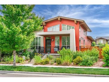 Charming two-story home with orange siding, inviting front porch, and well-manicured landscaping at 2868 Kingston St, Denver, CO 80238