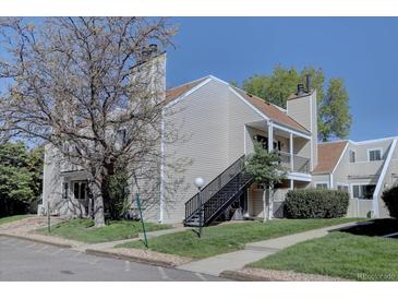 Inviting multi-story exterior with a black staircase, tan siding, and well-manicured lawn and landscape at 13633 E Yale Ave # B, Aurora, CO 80015