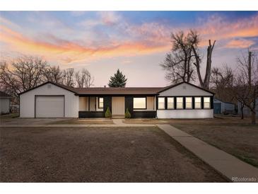 Charming single-story home with a detached garage, a well-maintained lawn, and a beautiful sunset backdrop at 11640 W 13Th Ave, Lakewood, CO 80401