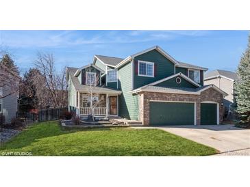 Inviting two-story home showcasing green siding, brick accents, and a well-maintained lawn and landscaping at 2829 S Fig St, Lakewood, CO 80228