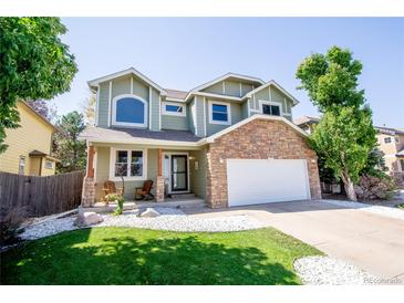 Charming two-story home with a stone facade, lush lawn, and inviting front porch seating at 57 N 45Th Ave, Brighton, CO 80601