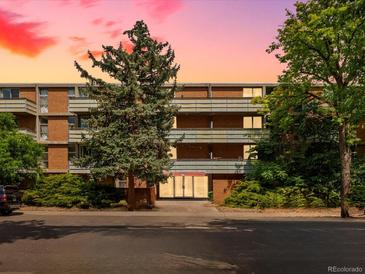 Brick apartment building exterior with lush trees and manicured bushes at dusk at 2500 S York St # 204, Denver, CO 80210