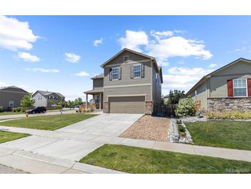 Charming two-story home features a well-manicured lawn, attached two car garage, and stone detailing at 603 Jewel St, Brighton, CO 80603