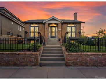 Brick home featuring arched windows, a chimney and professional landscaping at 4495 Utica St, Denver, CO 80212