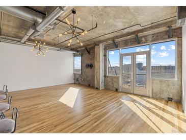 Bright living room boasts hardwood floors, exposed ductwork, and floor to ceiling windows with city views at 2020 Arapahoe St # 970, Denver, CO 80205