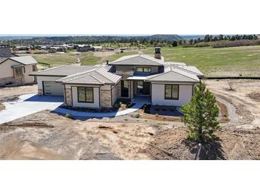 Stunning exterior elevation showing landscaping, tile roof, and great curb appeal at 6176 Oxford Peak Ln, Castle Rock, CO 80108