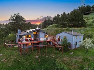 Charming home featuring an expansive deck, solar panels, and a separate guest house, all nestled in a lush, wooded landscape at 812 Aspen Rd, Golden, CO 80401