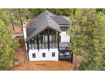 Striking two-story modern home with floor to ceiling windows and an inviting deck surrounded by lush green trees at 13910 Blue Jay Ln, Larkspur, CO 80118