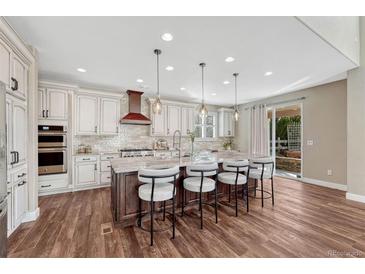 Bright kitchen features an island with seating, pendant lights, and stainless steel appliances at 10761 Hillsboro Cir, Parker, CO 80134