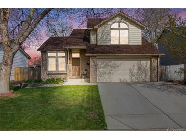 Charming two-story home with brick accents, manicured lawn, and an attached two-car garage at 9032 W Arizona Dr, Lakewood, CO 80232