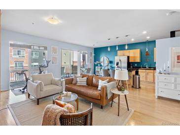 Bright living room featuring hardwood floors, a modern leather sofa, and balcony access at 1438 Little Raven St # 310, Denver, CO 80202