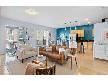 Bright living room featuring hardwood floors, comfortable seating, and an open floor plan with balcony access at 1438 Little Raven St # 310, Denver, CO 80202
