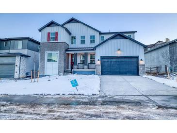 Two-story home with gray siding, a blue garage door, and a snowy front yard at 8512 Orchard City Dr, Littleton, CO 80125