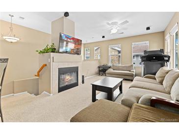 Comfortable living room featuring a cozy fireplace, entertainment center, and ample seating at 32 Whitehaven Cir, Highlands Ranch, CO 80129