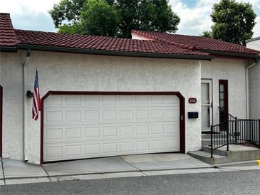 Exterior view of home featuring a two-car garage, red-tiled roof, and American flag at 1511 Belero St, Broomfield, CO 80020