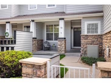 Charming townhome featuring a covered front porch with stone accents and a cozy seating area at 14000 Winding River Ct # T3, Broomfield, CO 80023