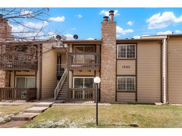 Exterior view of the home featuring a stone chimney, balcony, and well-maintained lawn at 1842 S Pitkin Cir # A, Aurora, CO 80017