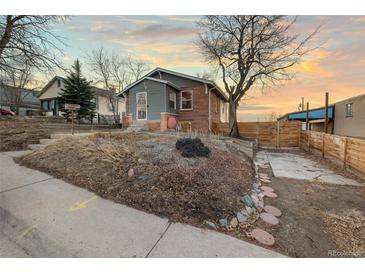 Charming exterior showcasing a two-story house with a unique stone front, landscaped yard, and tree at 1047 Meade St, Denver, CO 80204