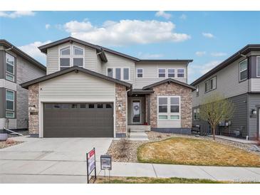 Charming two-story home with stone and siding, showcasing a well-manicured front yard and an attached two-car garage at 1660 Candleflower Dr, Castle Pines, CO 80108