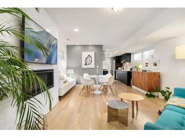 Open-concept living room with hardwood floors, fireplace, and modern furnishings at 3435 Lawrence St, Denver, CO 80205