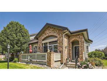 Charming home featuring a stone facade and inviting front porch with decorative accents and well-manicured landscaping at 2700 W Greens Pl, Littleton, CO 80123