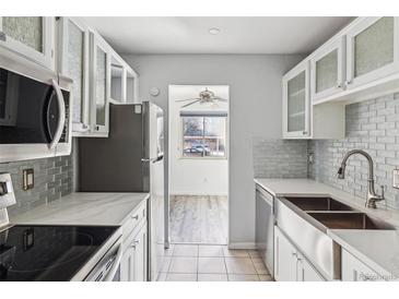 Updated kitchen featuring stainless steel appliances, white cabinets, and a view to an adjacent living space at 7995 E Mississippi Ave # J1, Denver, CO 80247