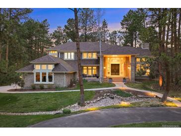 Charming home exterior with manicured lawn, stone accents, and inviting walkway through a wooded area at 510 Castle Pines Dr, Castle Rock, CO 80108