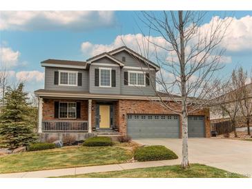 Charming two-story home with a well-manicured lawn, a yellow front door, and a three-car garage at 6488 S Kewaunee Way, Aurora, CO 80016