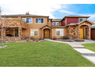 Inviting townhome featuring a stone archway entrance, landscaped yard, and a well-maintained green lawn at 8571 Gold Peak Dr # C, Highlands Ranch, CO 80130